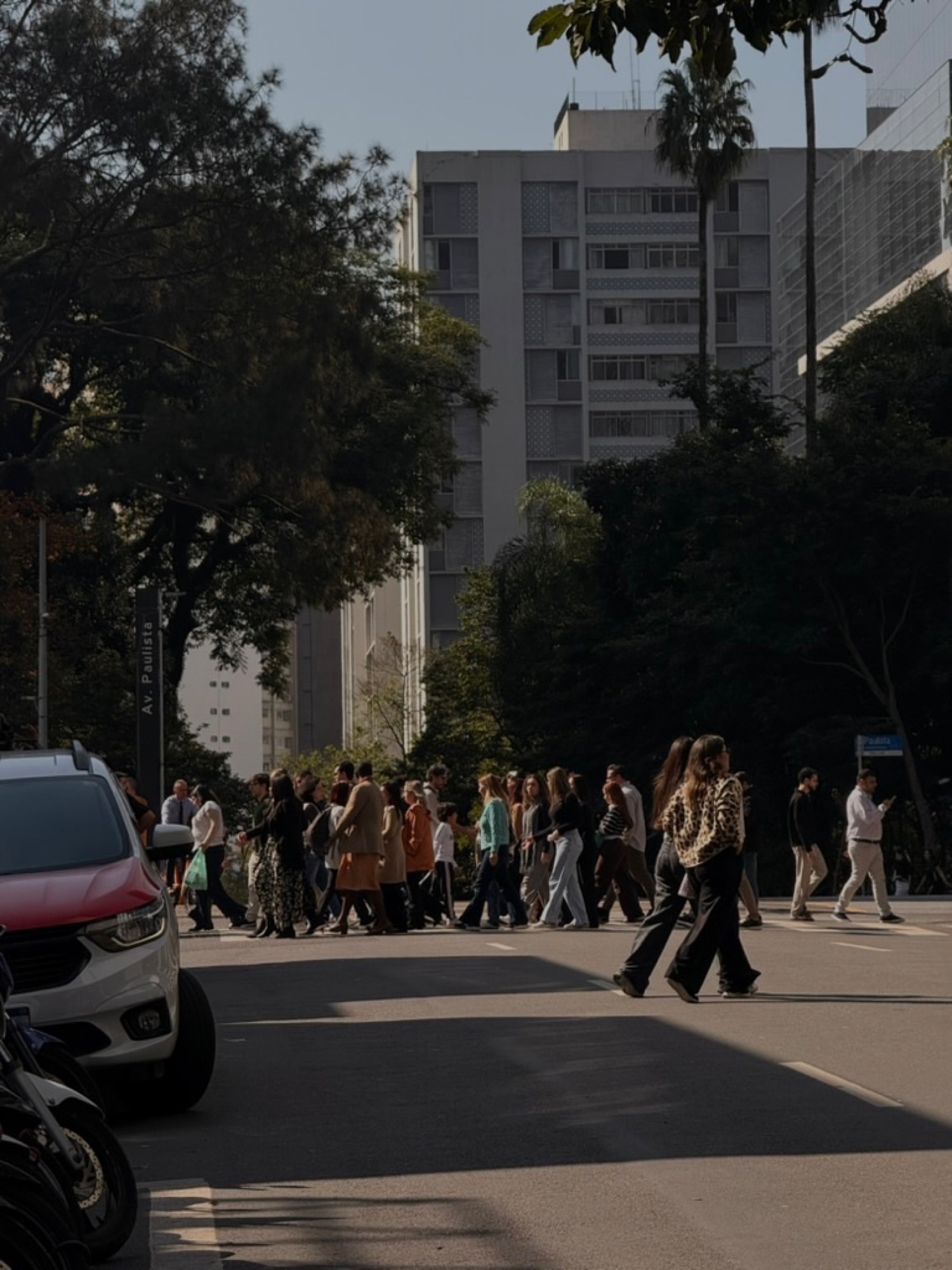 Crowd crossing Avenida Paulista in late-afternoon light